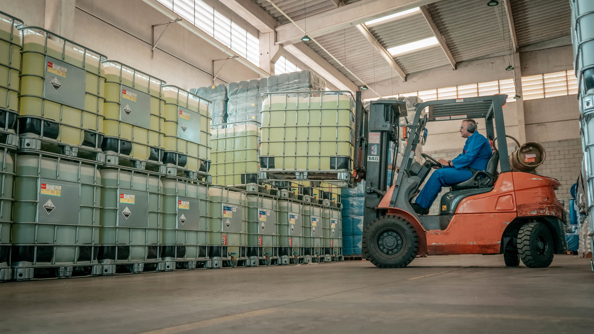 Operador movimentando tanques de produtos químicos no armazém da Hanaoka com empilhadeira